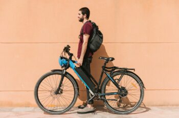 Man standing with an electric bike against orange background.